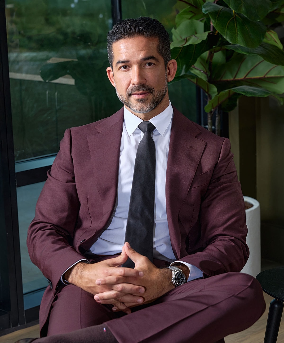 Man in a suit sitting confidently indoors.