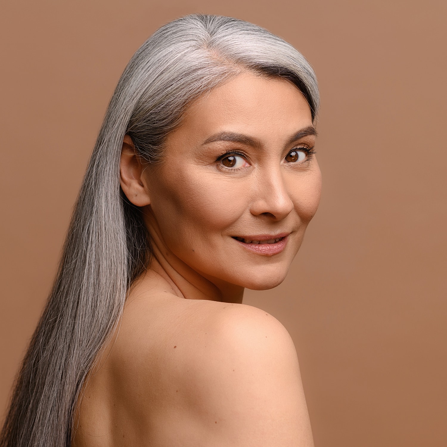 Woman with long gray hair against neutral background.