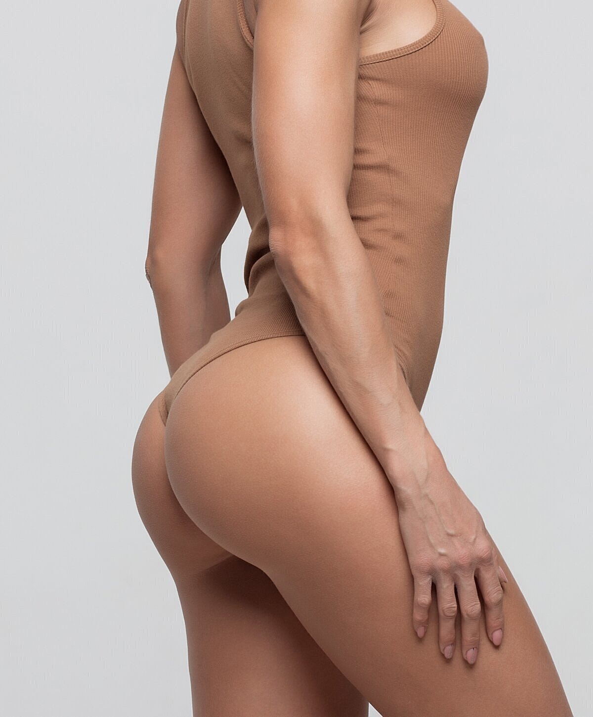 Model in brown bodysuit posing sideways.