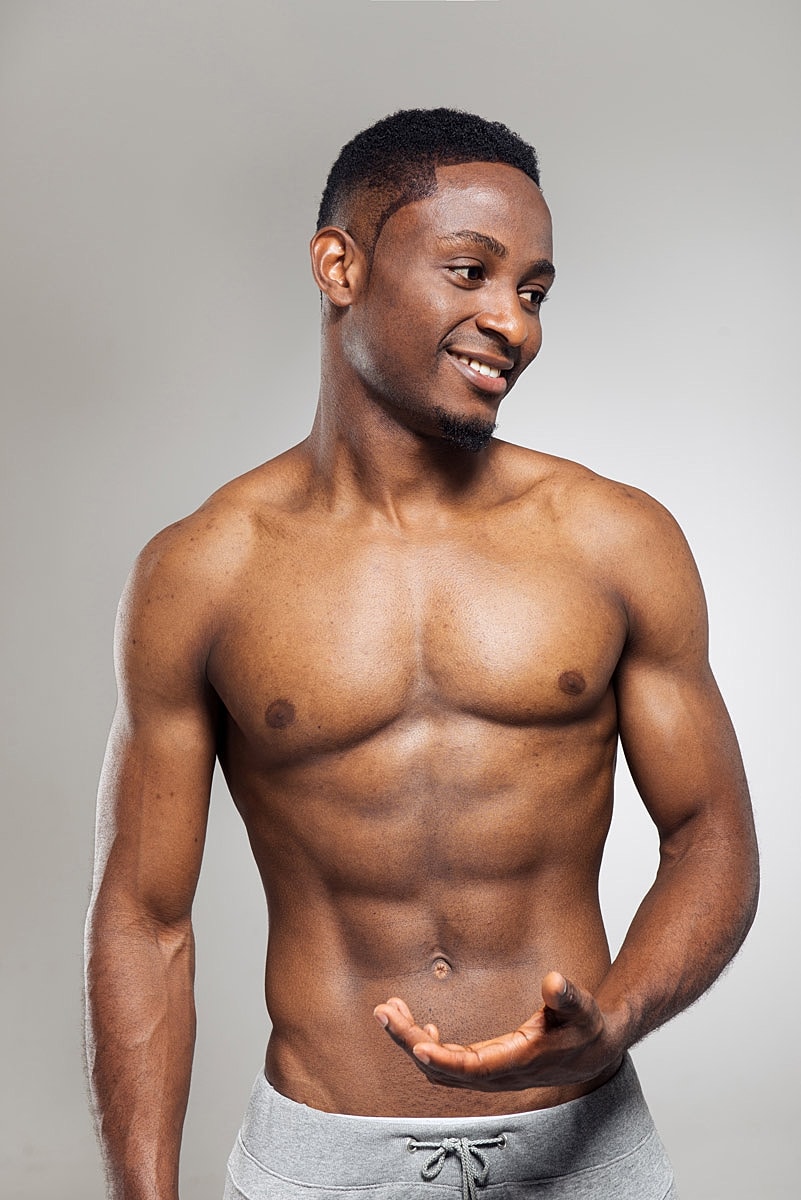 Smiling man with athletic build, gray shorts.