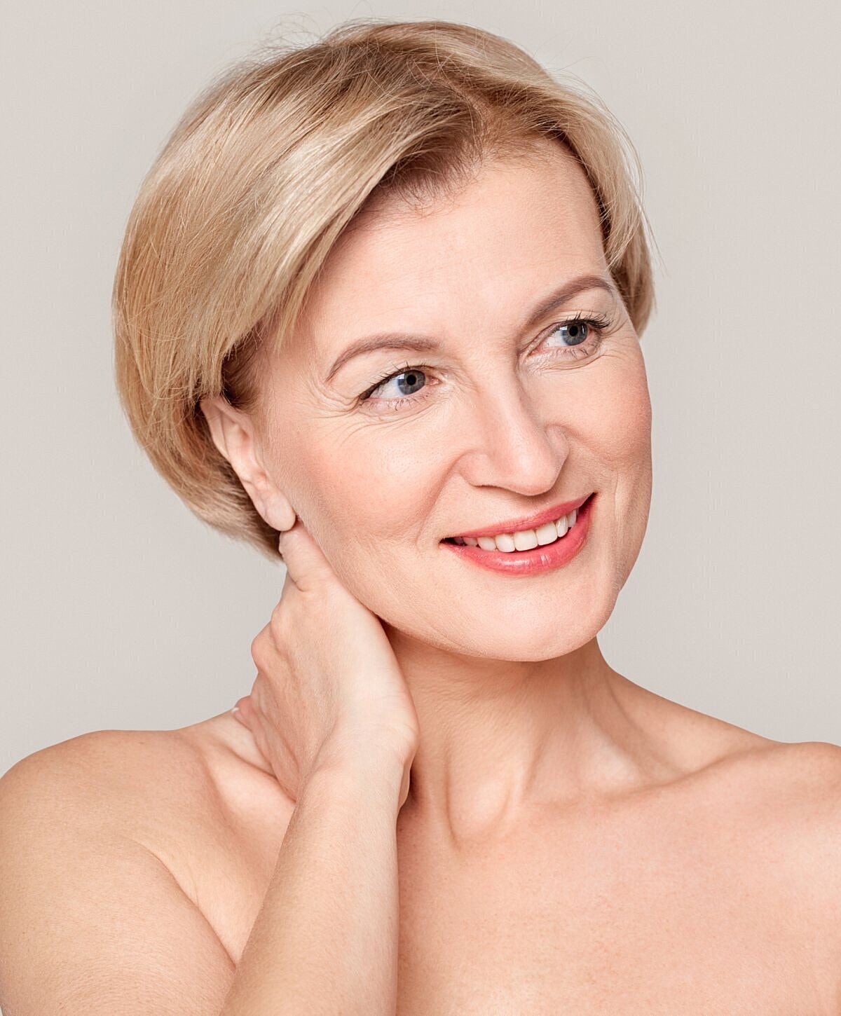 Smiling woman with short blonde hair, neutral background.