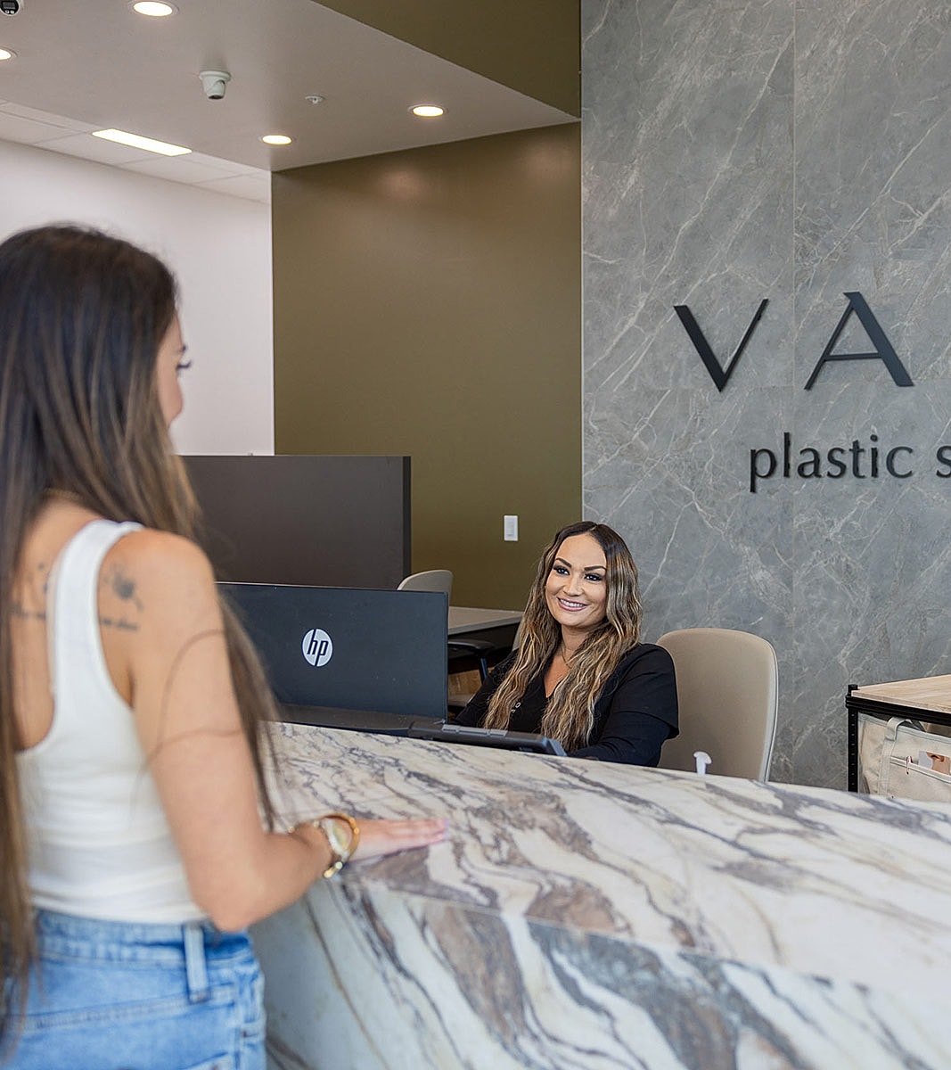 Receptionist greeting a client at plastic surgery office.
