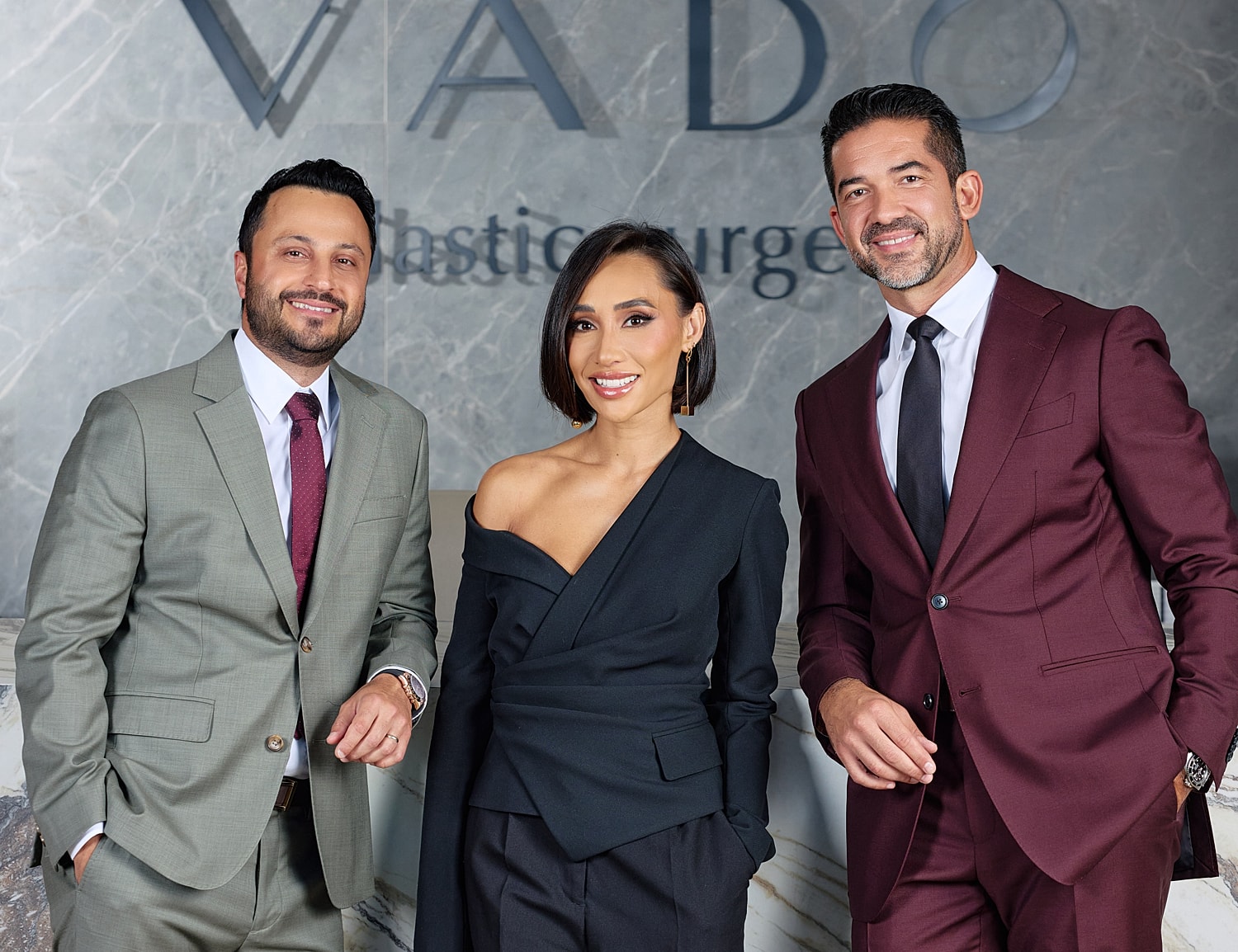 Three professionals posing at plastic surgery office.