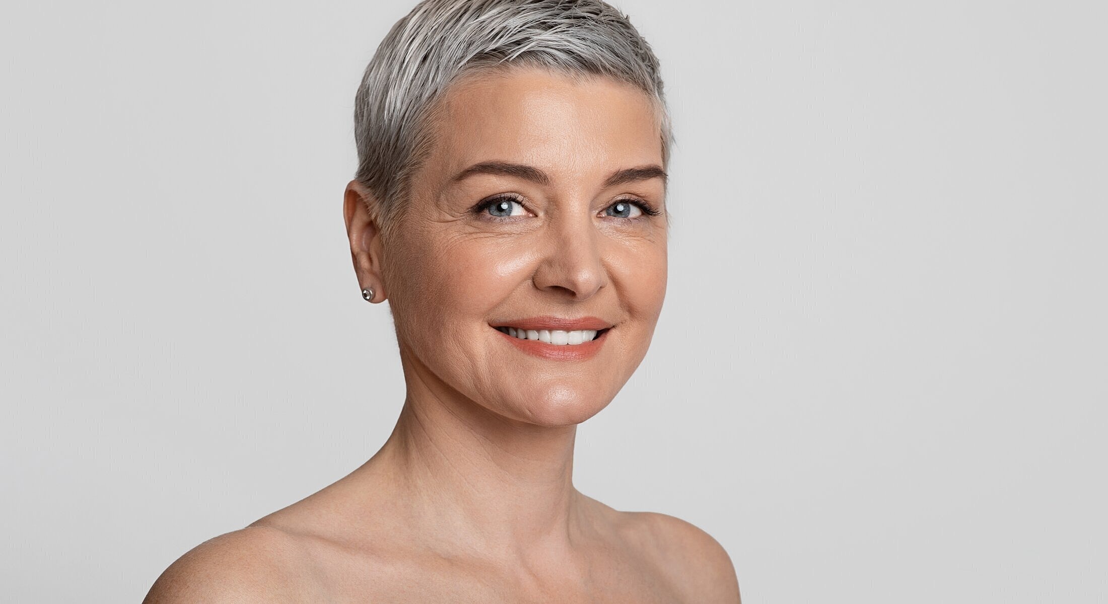 Smiling woman with short gray hair and earrings.
