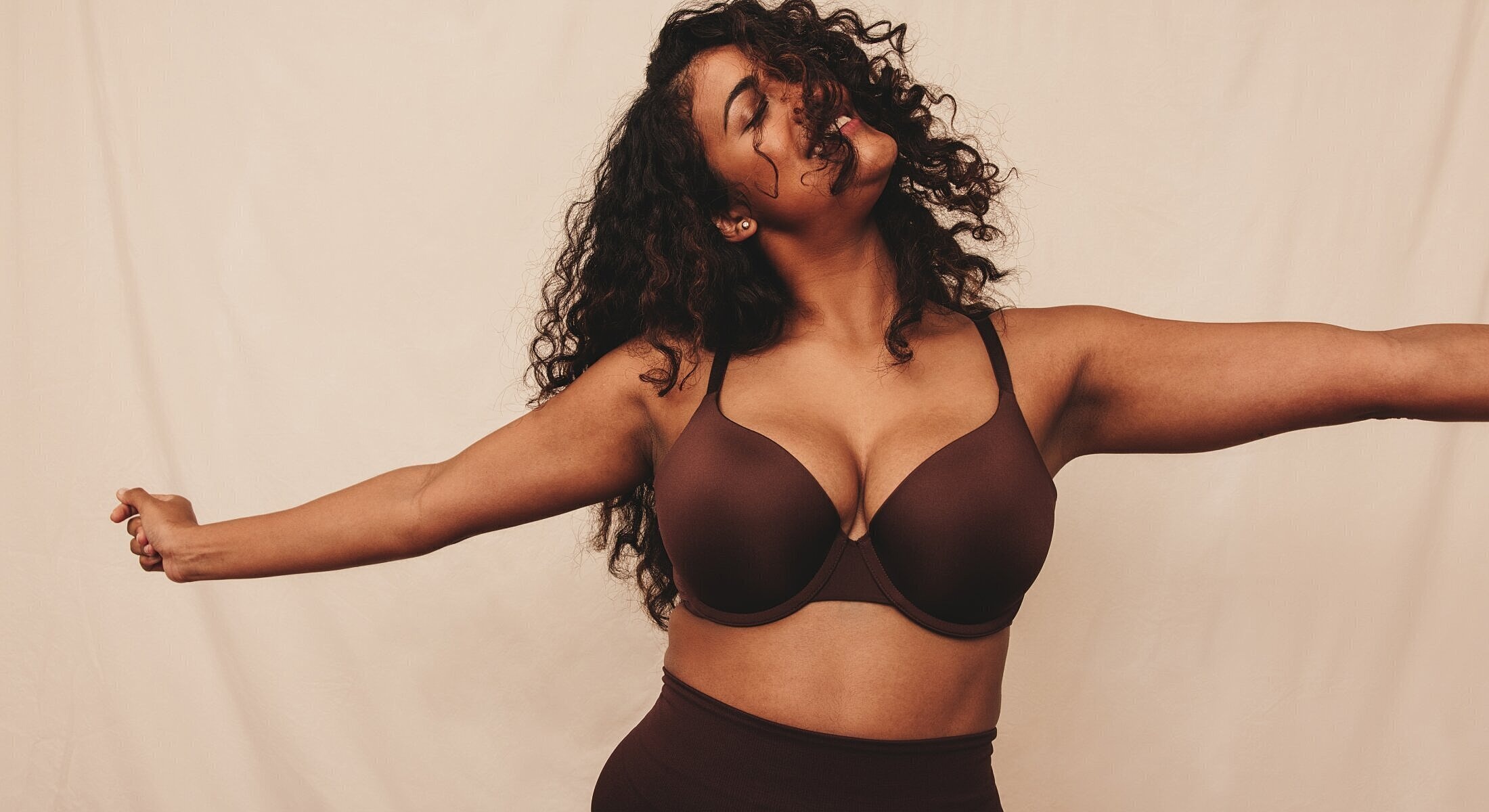 Woman in brown lingerie with joyful expression.