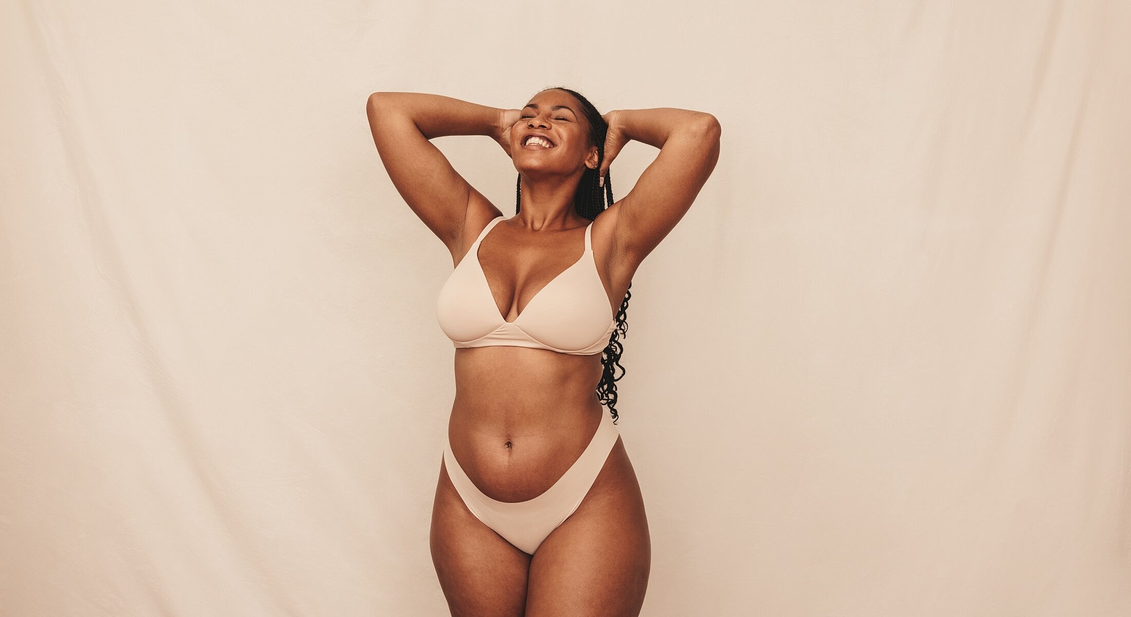 Smiling woman posing in neutral swimwear background.