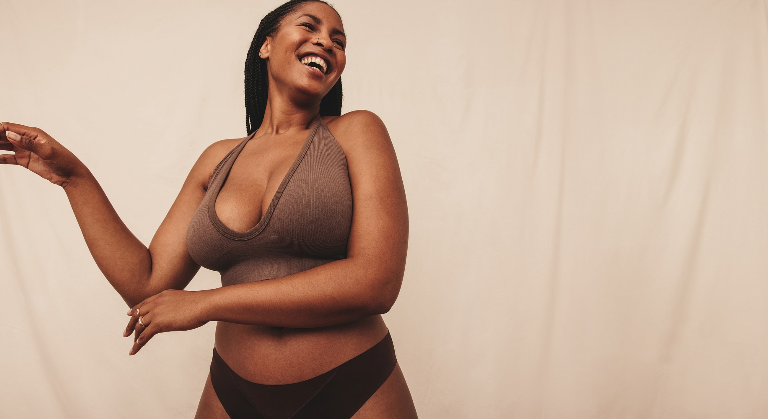 Woman in brown clothing smiling joyfully.