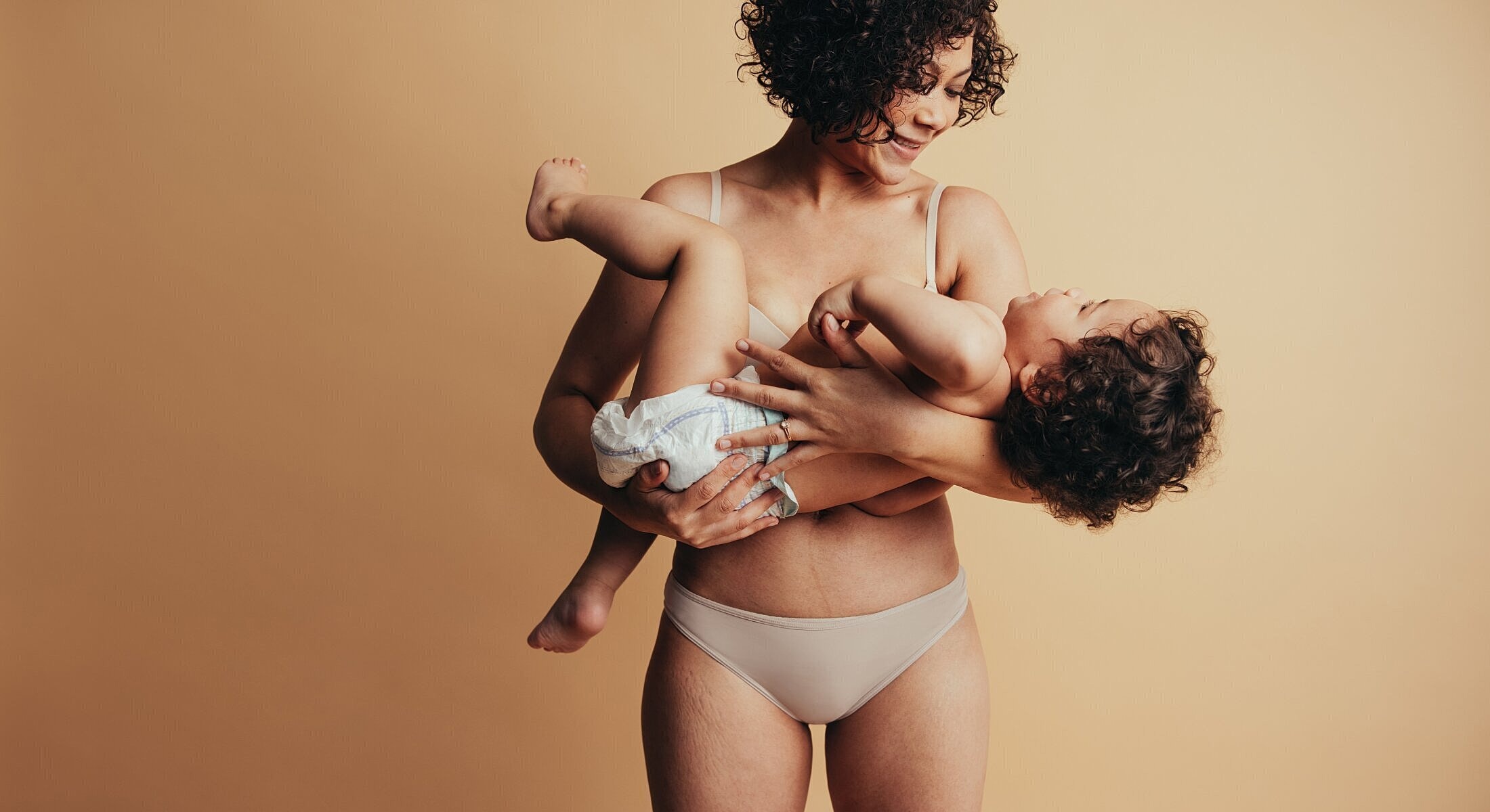 Mother holding child against neutral background.