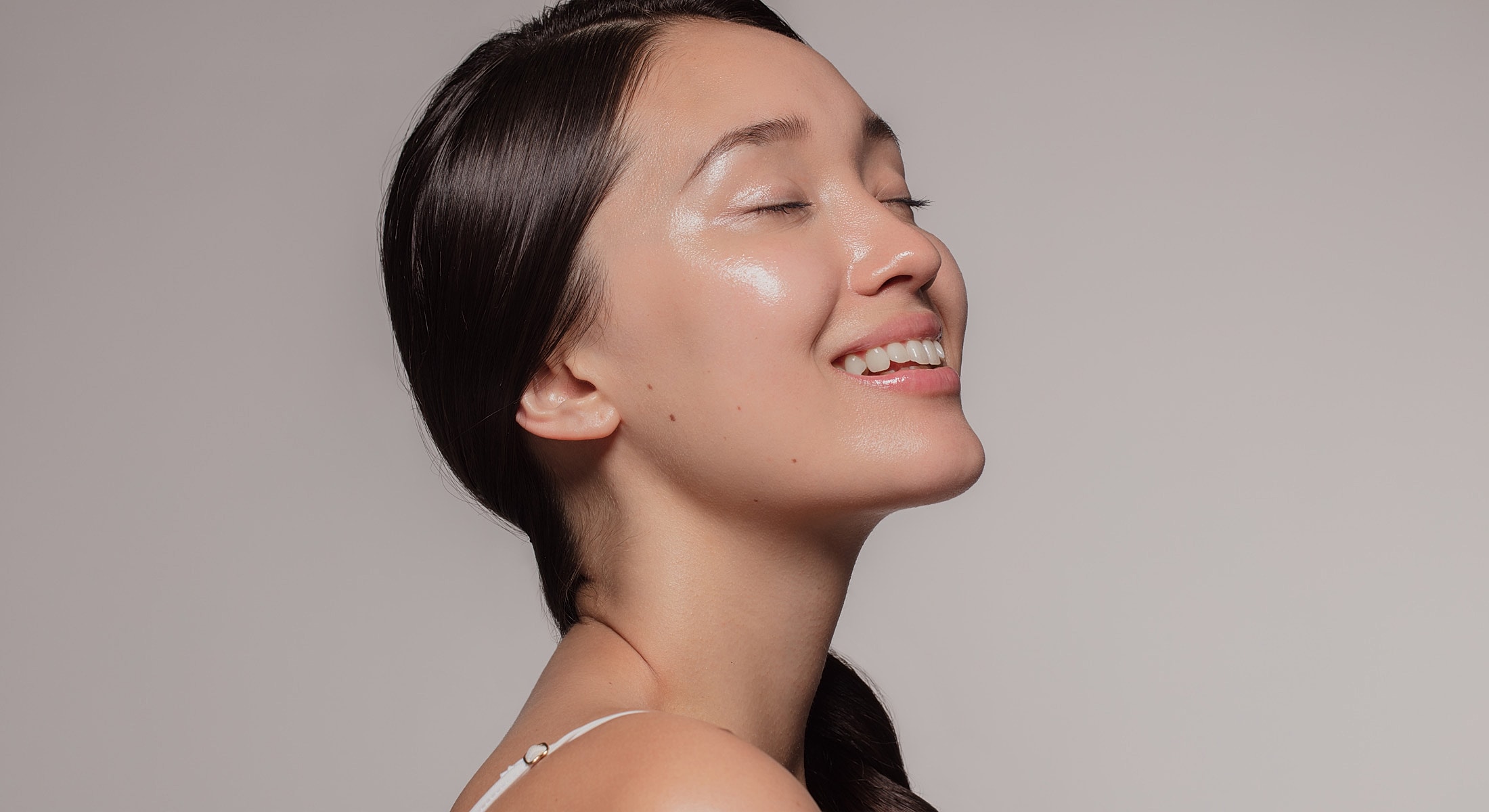 Woman smiling with closed eyes and glowing skin.