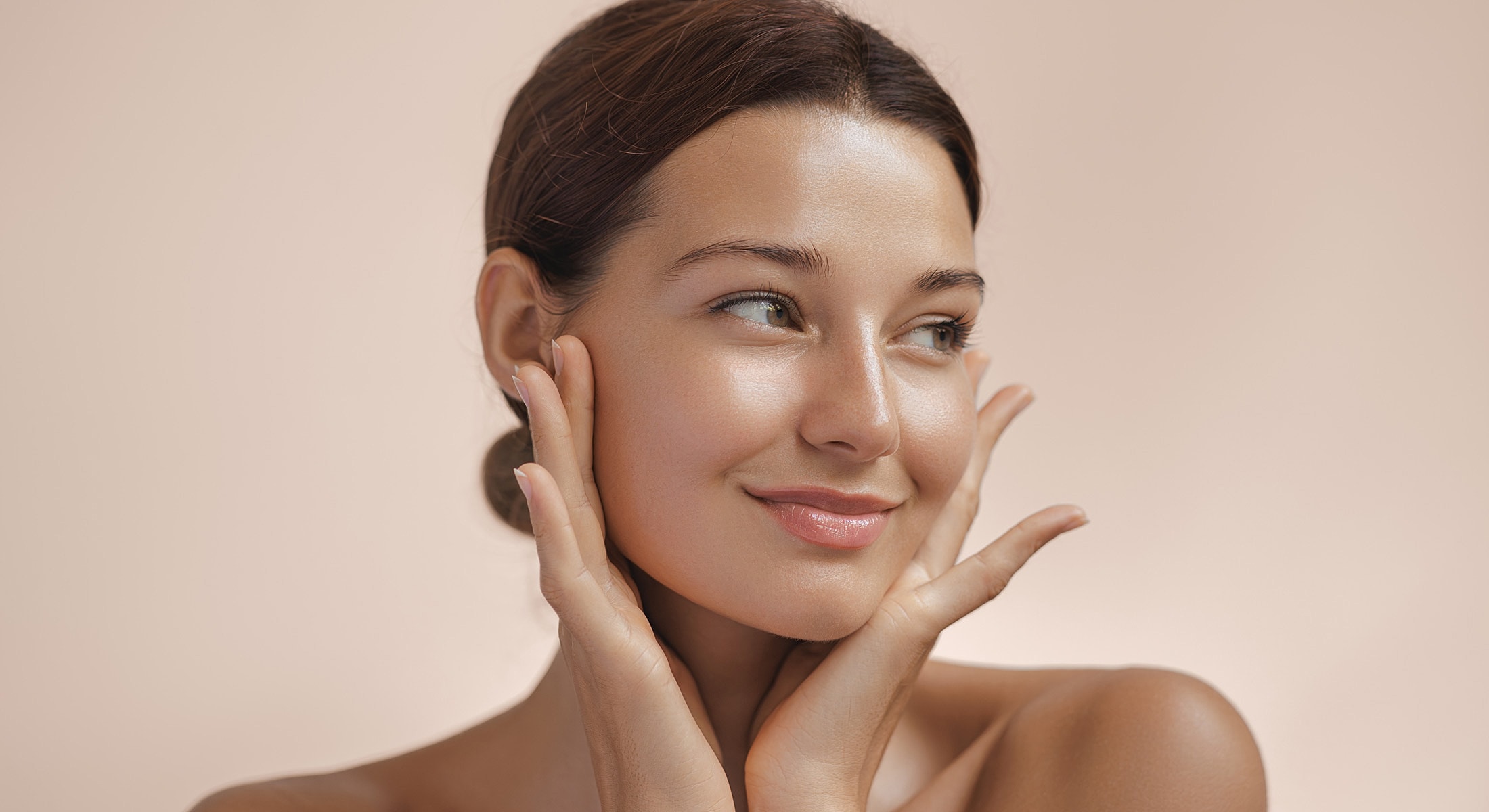 Smiling woman with glowing skin and soft background.